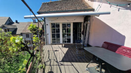 Private Dachterrasse mit Holzboden, roter Sitzbank, Tisch und Sonnenstoren am Altstadthaus Laufenburg CH.