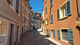 Kopfsteingepflasterte Laufengasse in der historischen Altstadt von Laufenburg CH mit farbigen Hausfassaden und Fensterläden.