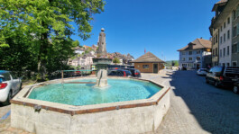 Laufenplatz in Laufenburg CH mit historischem Brunnen und Blick zur alten Rheinbrücke nach Laufenburg DE.
